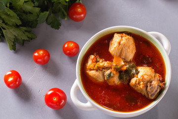 Chakhokhbili with chicken legs, parsley and tomatoes on a gray background. Chicken in tomato sauce.
