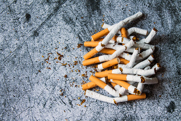 A pile of broken cigarettes on a gray textural background. The concept of a healthy lifestyle, quitting Smoking