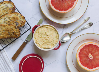 breakfast on the marble table. bread toasts, grapefruits and light chicken pate in a red bowl on...