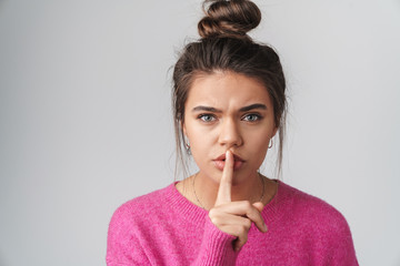 Image of nice displeased woman in pink sweater gesturing silence sign