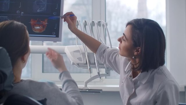 An orthodontist discusses an MRI scan with a patient sitting in a chair