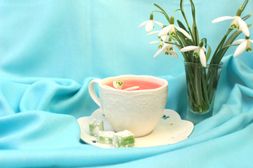 a Cup of pink tea on a blue background, spring mood over a Cup of tea, snowdrops