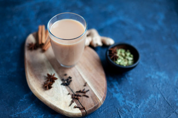 Obraz na płótnie Canvas Traditional indian drink - masala tea with spices on dark blue background