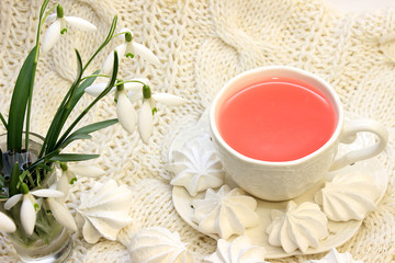 Cup of pink tea, spring meringue dessert with snowdrops
