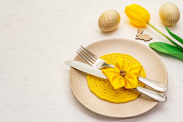 Easter table setting on textured white putty background. Spring holiday card template. Cutlery,...