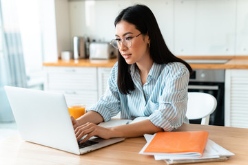 Concentrated brunette young woman using laptop computer