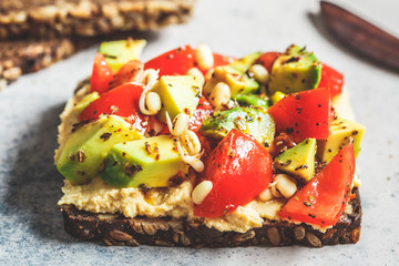 Avocado, hummus and tomato toast with seedlings. Healthy vegan food concept.