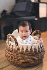 Asian baby boy in basket at home