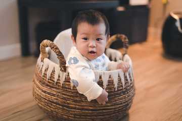 Asian baby boy in basket at home