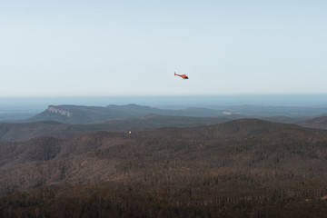 Mount Comboyne - December 30th 2019: A helicopter drops water on a spot fire as seen from the top of Mount Comboyne.