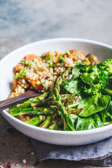 Vegan lunch bowl with quinoa, broccoli, asparagus and mushroom sauce in white bowl.