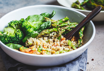 Vegan lunch bowl with quinoa, broccoli, asparagus and mushroom sauce in white bowl.