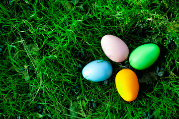 four multi-colored Easter eggs lie in the green grass. Easter background. Easter decoration.