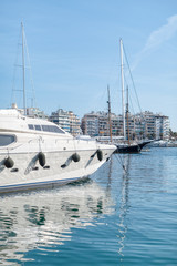 Pier with moored yachts in port. High class lifestyle. Luxury summer vacation. Balearic islands, Majorca. Maritime walking. Yachting sport. Marina with anchored sailboats. Houses on background.