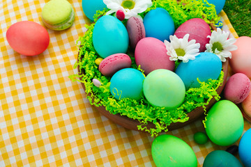 Fototapeta na wymiar Easter composition with colored eggs and bright candies on yellow tablecloth