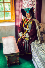 Fototapeta premium Portrait of a woman in traditional tibetan clothes inside her house in Ladakh, Kashmir, India