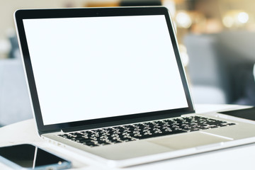 Fototapeta premium Close up of modern laptop with blank screen on white table in sunny interior, mockup. Business and technology concept