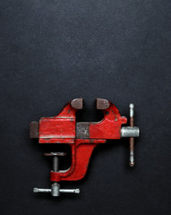 Metalwork tool - red vintage mechanical hand vise clamp on grey background with copy space, top...