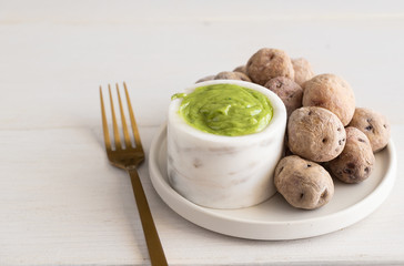  Papas Arrugadas (wrinkly potatoes with salt) and Mojo verde (green sauce) on wooden table.Typical Canary Islands dish l background with Copy space
