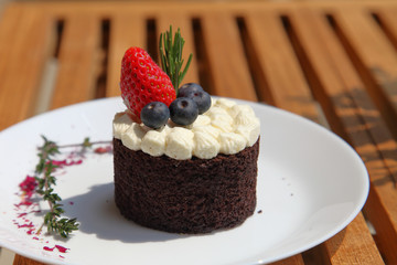 chocolate cake with strawberry and blueberry topping on wooden table with copy space