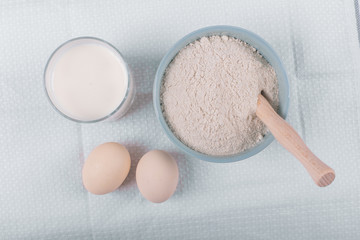 Sugar bowl with a cup of milk and eggs around. Top view