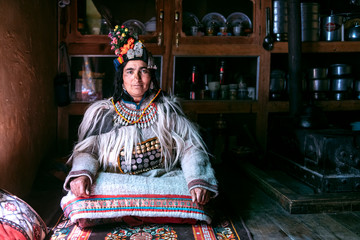 Portrait of a woman in typical tibetan clothes inside her house in Ladakh, Kashmir, India. - 325681114
