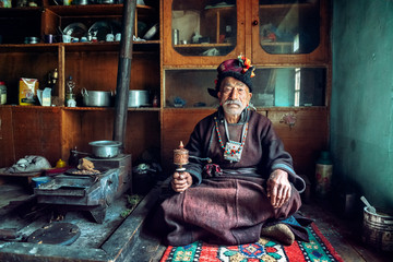 Portrait of an old man in typical tibetan clothes inside his house in Ladakh, Kashmir, India.