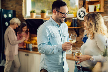 Happy couple drinking wine ad talking in the kitchen.
