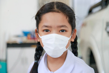 Fototapeta na wymiar Little Asian girl in Thai student uniform wearing virus protective flu mask, Health care concept, select focus shallow depth of field
