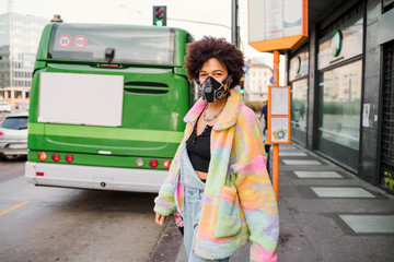 Young woman walking outdoor in Milan wearing medical mask protecting from pollution and virus