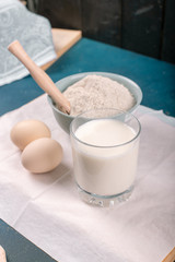 A cup of milk, eggs and a flour bowl