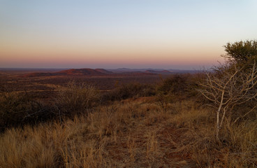 Sunset from a hill looking down over the hills and plains below at the Madikwe Game Reserve in South Africa.