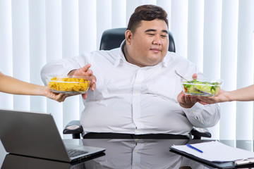 Fat Asian businessman preferring salad over chips