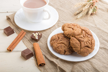 homemade oatmeal cookies with a cup of cocoa on a white wooden background. side view, close up.