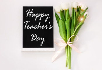 Internanional Teacher's day poster design with sign on black chalkboard and tulip flowers on white background.Message written on blackboard display.Greeting card back to school concept,flat lay banner