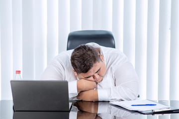 Fat Asian man sleeping while working in his office