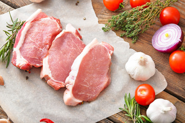 Raw pork meat and vegetables on wooden background