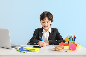 Little boy doing homework against color background