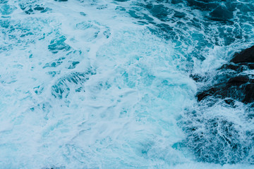 White sea foam produced when the waves collide with the rocks of the coast