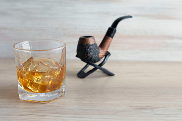 Tobacco pipe and whiskey on a wooden table