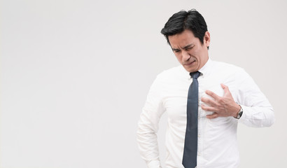 Asian office worker holding his chest, suffering from heart pain, heart attack, stressful working, caused by high blood pressure or high cholesterol, concept of healthcare and medical treatment.