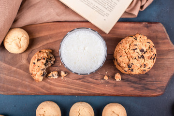 A glass of milk with sweet cookies on a wooden board. Top view