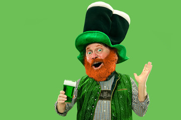 Pint of beer. Inviting. Excited leprechaun in green suit with red beard on green background. Funny...