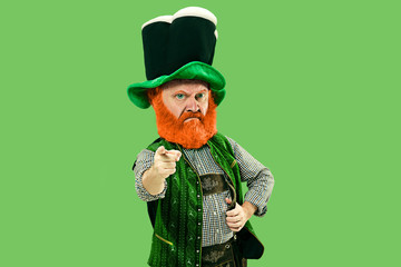 Pointing, choosing. Excited leprechaun in green suit with red beard on green background. Funny...