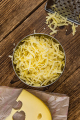 Wooden table with grated Cheese (close-up shot)