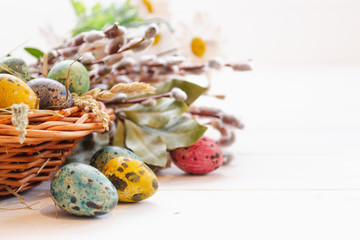 Easter eggs in a basket on a white wooden background