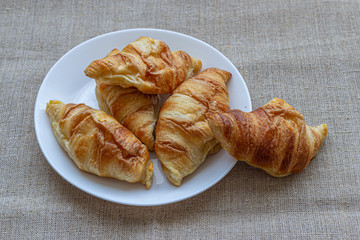 White plate with croissants on a canvas tablecloth