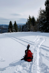 Fototapeta na wymiar backpack and hiking pole on snowy mountain hill