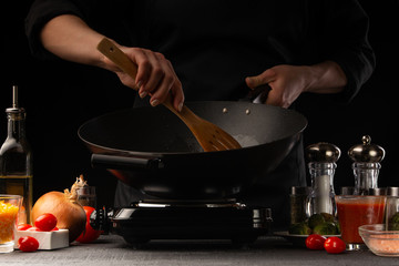 Chef cook. Frying a dish in a pan. Restaurant business, on a black background, horizontal photo. Ingredients, cafe or restaurant business.