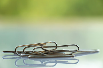Paper clip on white acrylic, Green garden background, Close up & Macro shot, Selective focus, Business, Education, Stationery concept